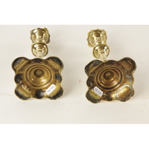 393 - A PAIR OF EARLY 18TH CENTURY SEAMED BRASS PETAL BASE CANDLESTICKS with twist stem ejectors, with rin... 