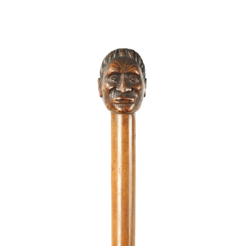 397 - A LATE 19TH CENTURY CARVED HARDWOOD WALKING STICK FORMED AS A MĀORI having facial decoration on a ta... 