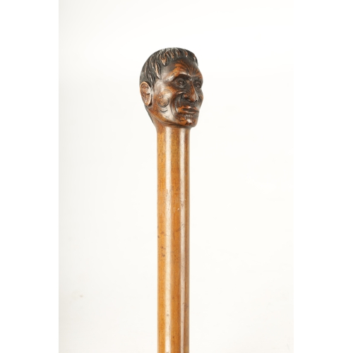 397 - A LATE 19TH CENTURY CARVED HARDWOOD WALKING STICK FORMED AS A MĀORI having facial decoration on a ta... 