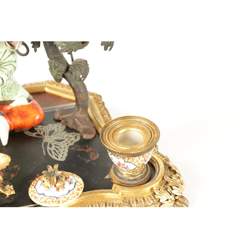 434 - A 19TH CENTURY CONTINENTAL ORMOLU, LACQUERWORK AND PORCELAIN PEN AND INK STAND with seated porcelain... 