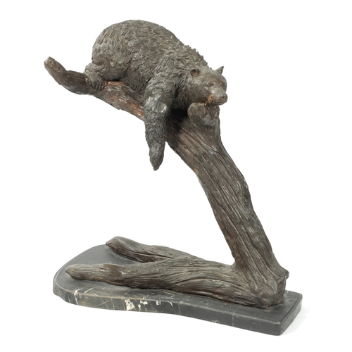 120 - A 20TH CENTURY BRONZE BEAR SCULPTURE depicting a bear sleeping in branch work; mounted on a black ma... 