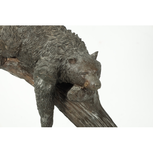 120 - A 20TH CENTURY BRONZE BEAR SCULPTURE depicting a bear sleeping in branch work; mounted on a black ma... 