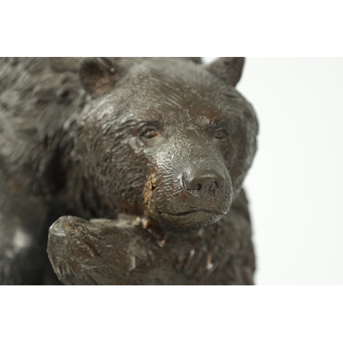 120 - A 20TH CENTURY BRONZE BEAR SCULPTURE depicting a bear sleeping in branch work; mounted on a black ma... 