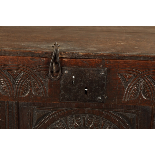 213 - A LARGE 17TH CENTURY CARVED THREE PANELLED OAK COFFER with plank top above arched leaf carved panels... 