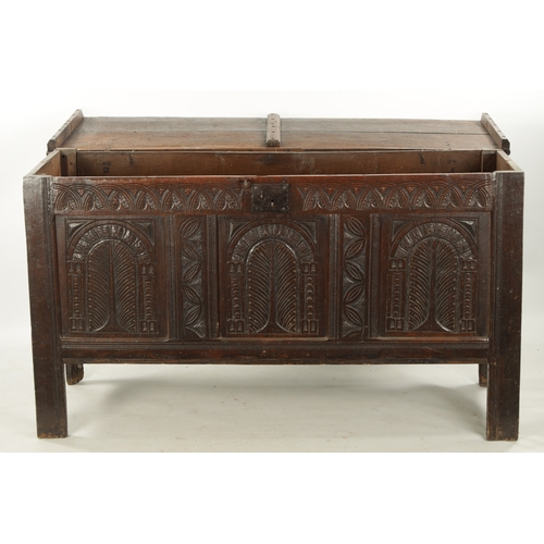 213 - A LARGE 17TH CENTURY CARVED THREE PANELLED OAK COFFER with plank top above arched leaf carved panels... 