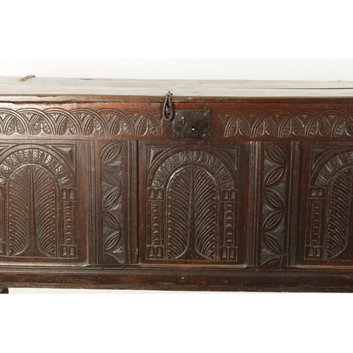 213 - A LARGE 17TH CENTURY CARVED THREE PANELLED OAK COFFER with plank top above arched leaf carved panels... 