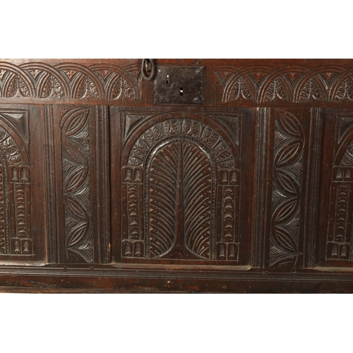 213 - A LARGE 17TH CENTURY CARVED THREE PANELLED OAK COFFER with plank top above arched leaf carved panels... 