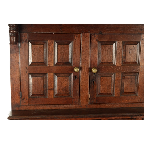 224 - AN EARLY 18TH CENTURY PANELLED OAK DUDARN with fielded panelled doors and frieze drawers (139cm wide... 