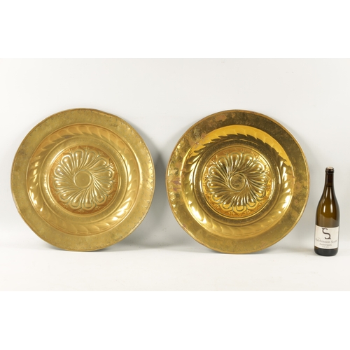 239 - A PAIR OF 17TH CENTURY BRASS ALMS DISHES with embossed swirl work decoration (49cm diameter)