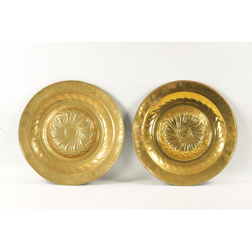 239 - A PAIR OF 17TH CENTURY BRASS ALMS DISHES with embossed swirl work decoration (49cm diameter)