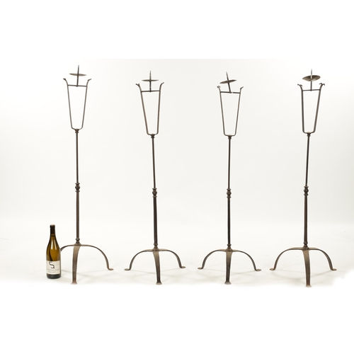 241 - A SET OF FOUR IRONWORK CHURCH FLOOR STANDING CANDLESTICKS with knopped stems and tripod bases (115cm... 