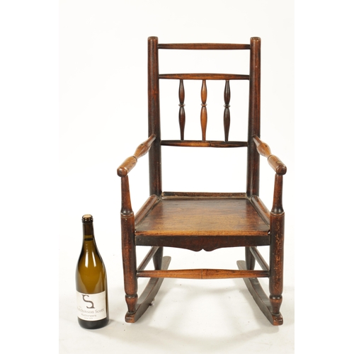 300 - A 19TH CENTURY ELM CHILD'S SPINDLE BACK ROCKING CHAIR with solid seat (70cm high 42cm wide)