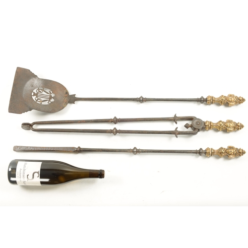 323 - A SET OF LATE GEORGIAN BRASS AND STEEL FIRE IRONS with cast brass rococo style handles