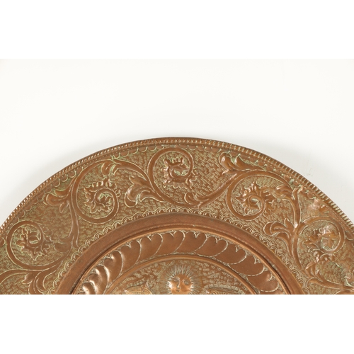 384 - A 16TH / 17TH CENTURY EMBOSSED COPPER ALMS DISH OF LARGE SIZE with figural centre surrounded by a le... 