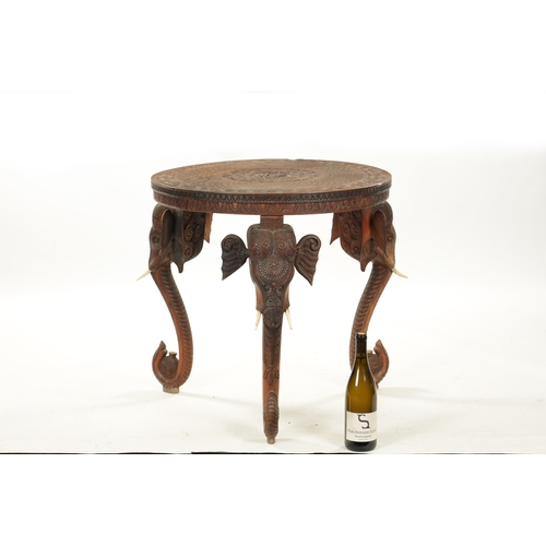 436 - A 19TH CENTURY INDIAN CARVED HARDWOOD OCCASIONAL TABLE the circular carved top above three elephant'... 