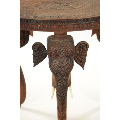 436 - A 19TH CENTURY INDIAN CARVED HARDWOOD OCCASIONAL TABLE the circular carved top above three elephant'... 