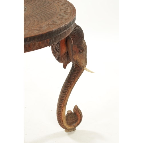 436 - A 19TH CENTURY INDIAN CARVED HARDWOOD OCCASIONAL TABLE the circular carved top above three elephant'... 