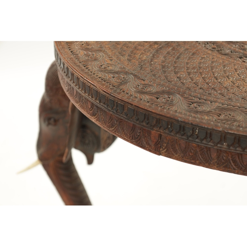 436 - A 19TH CENTURY INDIAN CARVED HARDWOOD OCCASIONAL TABLE the circular carved top above three elephant'... 