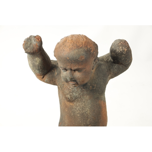 445 - AN EARLY 18TH CENTURY TERRACOTTA FIGURE OF STANDING CHERUB mounted on a later iron stand