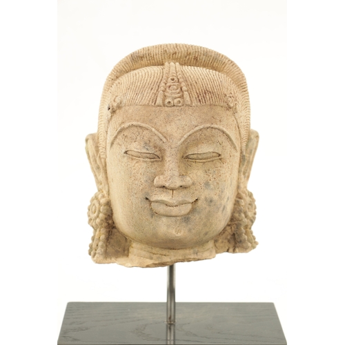 52 - A CARVED STONE HEAD OF AN INDIAN BUDDHA on a later ebonised base. (the head 21cm high 17cm wide)