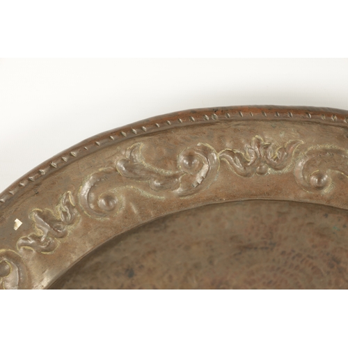 94 - AN EARLY 18TH CENTURY SPANISH EMBOSSED BRASS TWO HANDLED DISH with figural centre (50.5cm diameter)