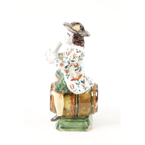 465 - AN 18TH / 19TH CENTURY DELFT POLYCHROME FIGURE modelled as a man sitting on a barrel drinking out of... 