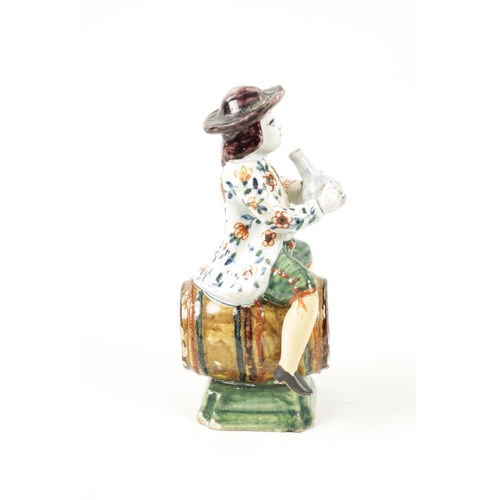 465 - AN 18TH / 19TH CENTURY DELFT POLYCHROME FIGURE modelled as a man sitting on a barrel drinking out of... 