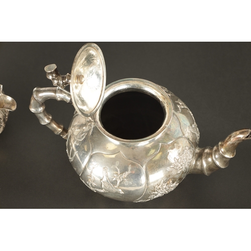 543 - A LATE 19TH CENTURY CHINESE SILVER THREE-PIECE TEA SET decorated in relief with birds among flowerin... 