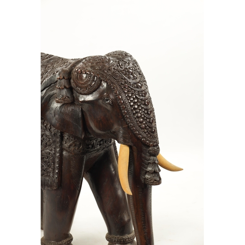 576 - A LARGE EARLY 20TH CENTURY CARVED HARDWOOD ELEPHANT finely carved with scrollwork foliage and stylis... 