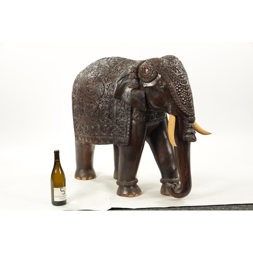 576 - A LARGE EARLY 20TH CENTURY CARVED HARDWOOD ELEPHANT finely carved with scrollwork foliage and stylis... 