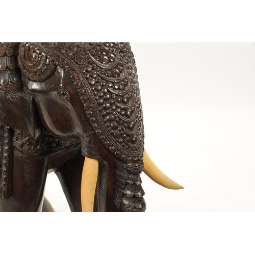 576 - A LARGE EARLY 20TH CENTURY CARVED HARDWOOD ELEPHANT finely carved with scrollwork foliage and stylis... 