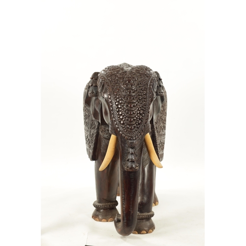 576 - A LARGE EARLY 20TH CENTURY CARVED HARDWOOD ELEPHANT finely carved with scrollwork foliage and stylis... 