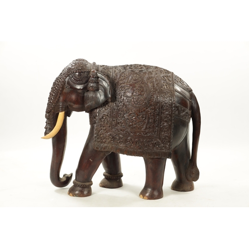 576 - A LARGE EARLY 20TH CENTURY CARVED HARDWOOD ELEPHANT finely carved with scrollwork foliage and stylis... 