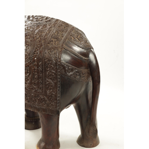 576 - A LARGE EARLY 20TH CENTURY CARVED HARDWOOD ELEPHANT finely carved with scrollwork foliage and stylis... 