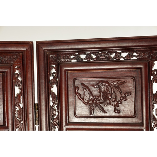 599 - AN EARLY 20TH CENTURY CHINESE FOUR-SECTION FOLDING SCREEN having pierced carved hardwood frames encl... 