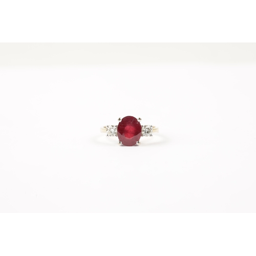 620 - AN 18CT GOLD RUBY AND DIAMOND RING having an oval cut ruby flanked by two brilliant cut diamonds all... 