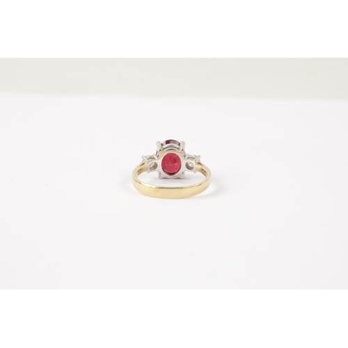 620 - AN 18CT GOLD RUBY AND DIAMOND RING having an oval cut ruby flanked by two brilliant cut diamonds all... 