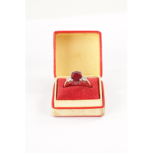 620 - AN 18CT GOLD RUBY AND DIAMOND RING having an oval cut ruby flanked by two brilliant cut diamonds all... 