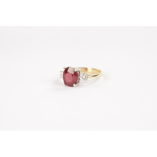 620 - AN 18CT GOLD RUBY AND DIAMOND RING having an oval cut ruby flanked by two brilliant cut diamonds all... 