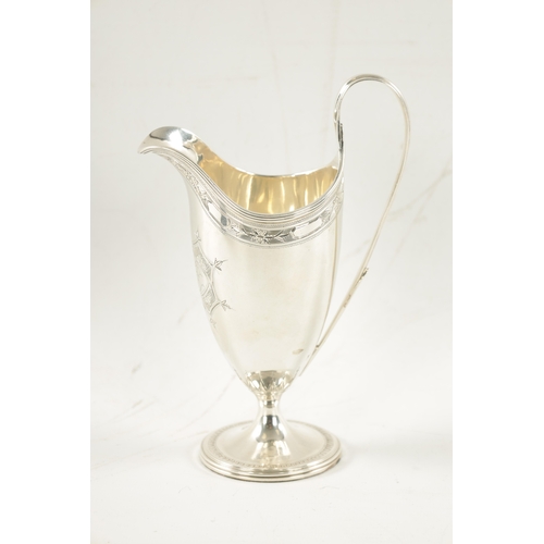 696 - A GEORGE III HELMET STYLE SILVER CREAM JUG with bright cut border and floral cartouche on circular f... 