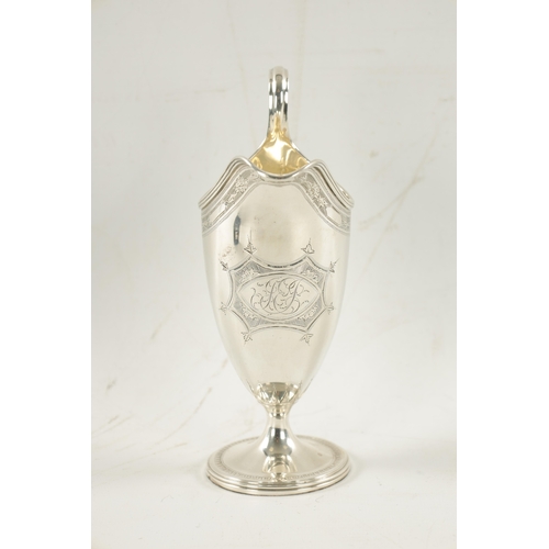 696 - A GEORGE III HELMET STYLE SILVER CREAM JUG with bright cut border and floral cartouche on circular f... 