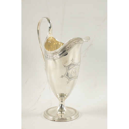 696 - A GEORGE III HELMET STYLE SILVER CREAM JUG with bright cut border and floral cartouche on circular f... 