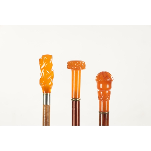 744 - A COLLECTION OF THREE LATE 19TH CENTURY AMBER TYPE TOPPED WALKING STICKS with moulded handles. (each... 