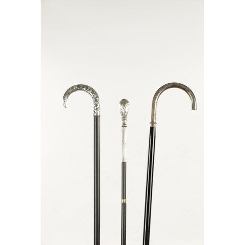 751 - A COLLECTION OF THREE ART NOUVEAU SILVER TOPPED WALKING STICKS two with hook handles, embossed and e... 