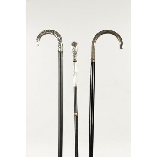 751 - A COLLECTION OF THREE ART NOUVEAU SILVER TOPPED WALKING STICKS two with hook handles, embossed and e... 