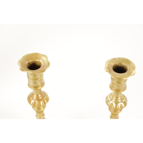 792 - A PAIR OF MID 18TH CENTURY SEAMED CAST BRASS CANDLESTICKS with square petal shaped bases and ringed ... 