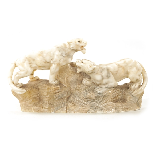 1012 - A 19TH CENTURY CARVED ALABASTER SCULPTURE OF TWO LIONS mounted on a naturalistic base (55cm wide)