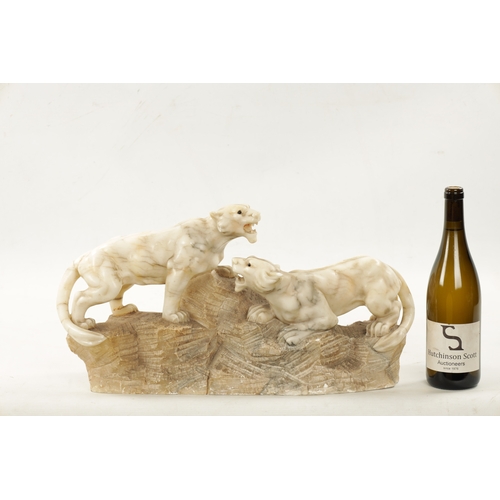 1012 - A 19TH CENTURY CARVED ALABASTER SCULPTURE OF TWO LIONS mounted on a naturalistic base (55cm wide)