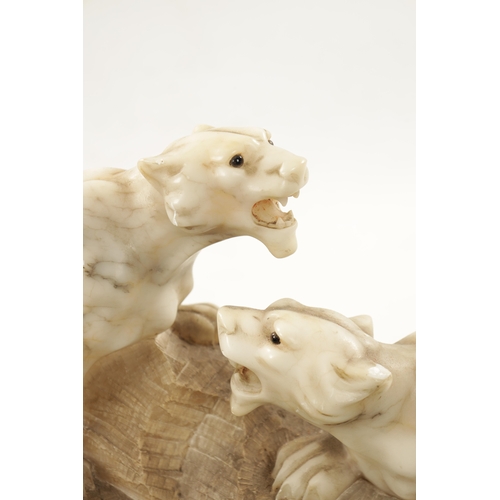 1012 - A 19TH CENTURY CARVED ALABASTER SCULPTURE OF TWO LIONS mounted on a naturalistic base (55cm wide)