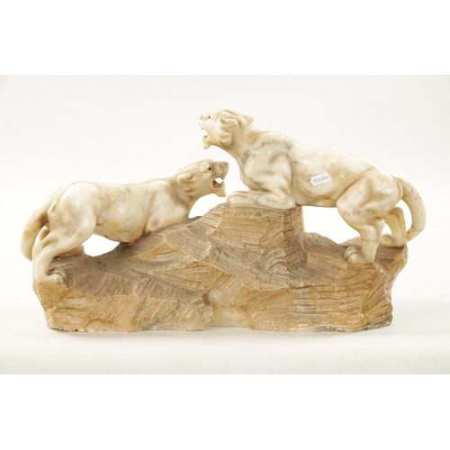 1012 - A 19TH CENTURY CARVED ALABASTER SCULPTURE OF TWO LIONS mounted on a naturalistic base (55cm wide)